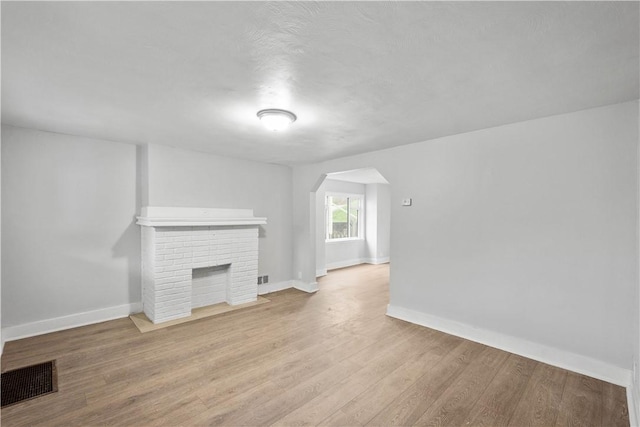 4 Gardner St, Etna, PA 15223 - unfurnished living room with arched walkways, visible vents, wood finished floors, a brick fireplace, and baseboards