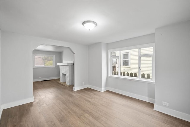 4 Gardner St, Etna, PA 15223 - unfurnished living room with arched walkways, a brick fireplace, baseboards, and wood finished floors