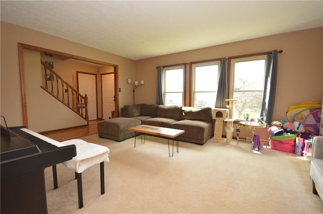 living room featuring stairway, carpet, and a healthy amount of sunlight