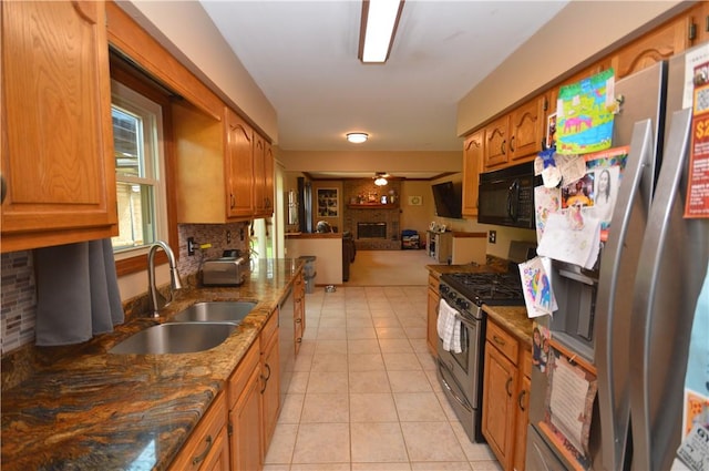 kitchen with appliances with stainless steel finishes, open floor plan, light tile patterned flooring, decorative backsplash, and a sink