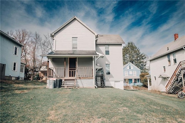 rear view of property with covered porch, stairs, and a lawn
