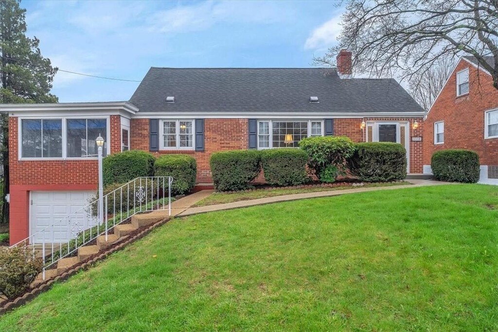 view of front of house featuring a garage, brick siding, a chimney, and a front lawn