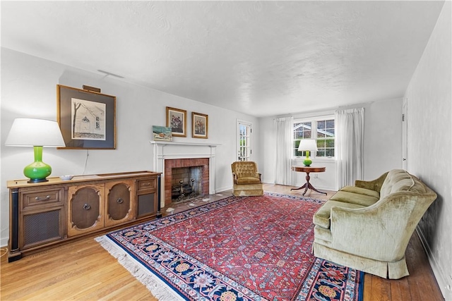 living area with a textured ceiling, wood finished floors, a fireplace, and baseboards