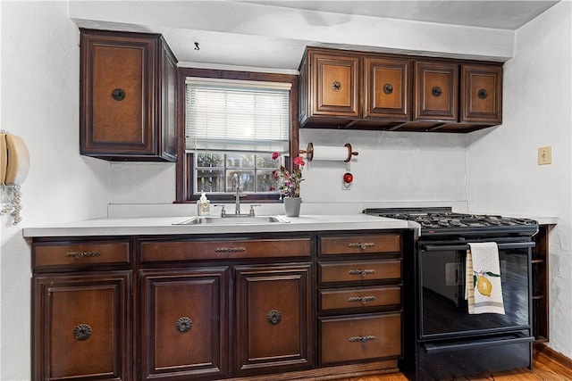 kitchen with light countertops, gas stove, a sink, and dark brown cabinets