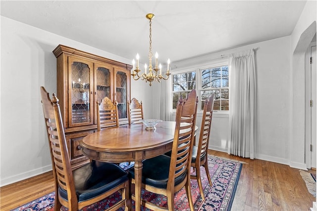 dining area with baseboards, an inviting chandelier, and wood finished floors