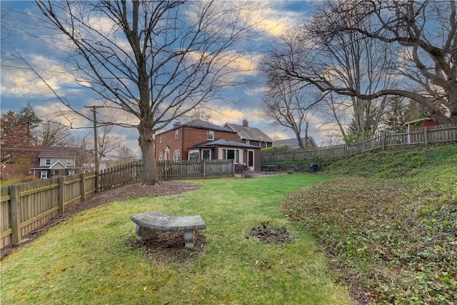 yard at dusk featuring a fenced backyard and a wooden deck
