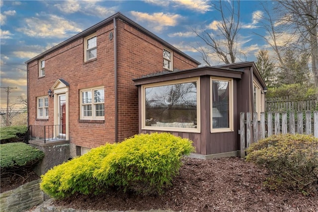 view of property exterior featuring fence and brick siding