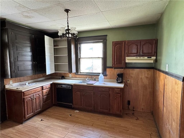 kitchen with under cabinet range hood, light wood-style flooring, black dishwasher, and wainscoting