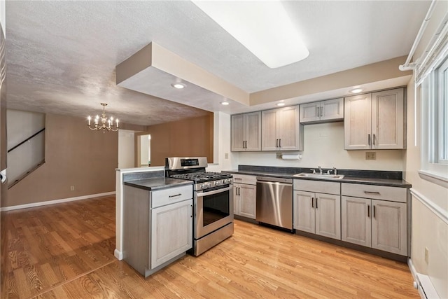 510 Brinton Ave, Pitcairn, PA 15140 - kitchen featuring light wood-style floors, an inviting chandelier, a sink, dark countertops, and stainless steel appliances