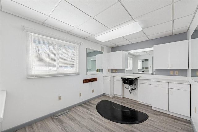 510 Brinton Ave, Pitcairn, PA 15140 - kitchen with baseboards, light countertops, white cabinetry, light wood finished floors, and a drop ceiling