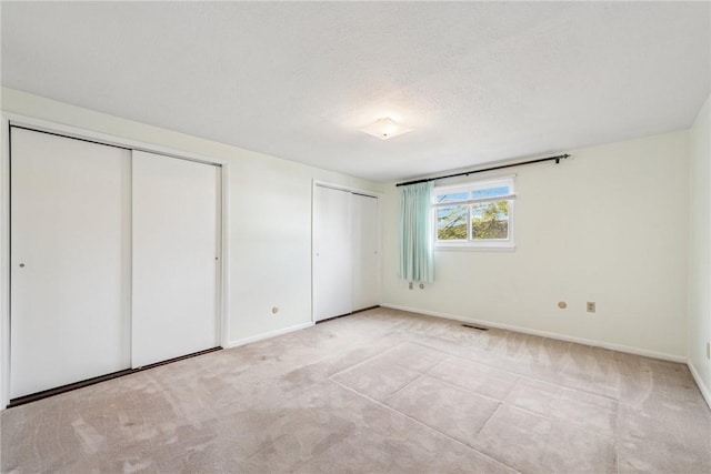 510 Brinton Ave, Pitcairn, PA 15140 - unfurnished bedroom featuring two closets, baseboards, visible vents, and carpet floors