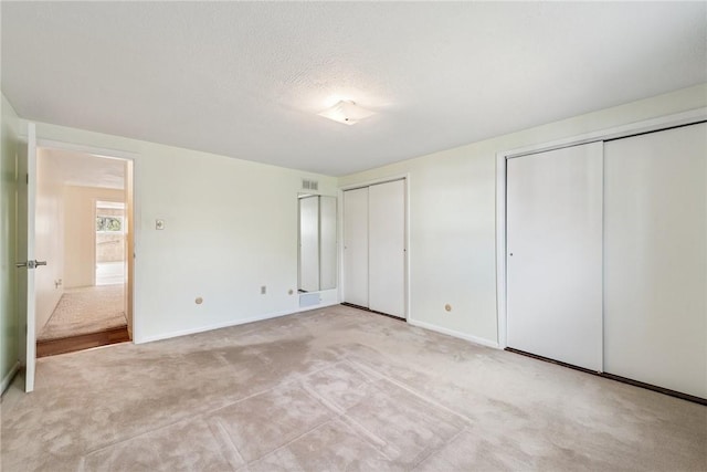 510 Brinton Ave, Pitcairn, PA 15140 - unfurnished bedroom featuring visible vents, baseboards, two closets, a textured ceiling, and carpet flooring