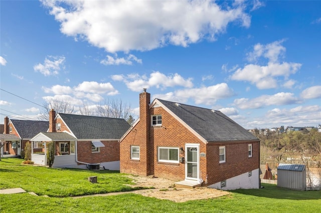 back of house with an outbuilding, brick siding, a shed, and a lawn
