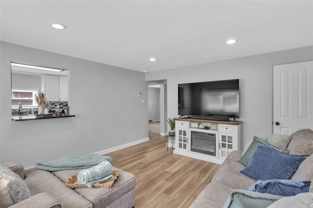living room with recessed lighting, light wood-style floors, and baseboards