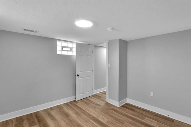 below grade area with wood finished floors, baseboards, and visible vents