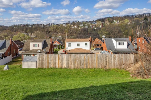 view of yard with a residential view, a storage shed, fence, and an outbuilding