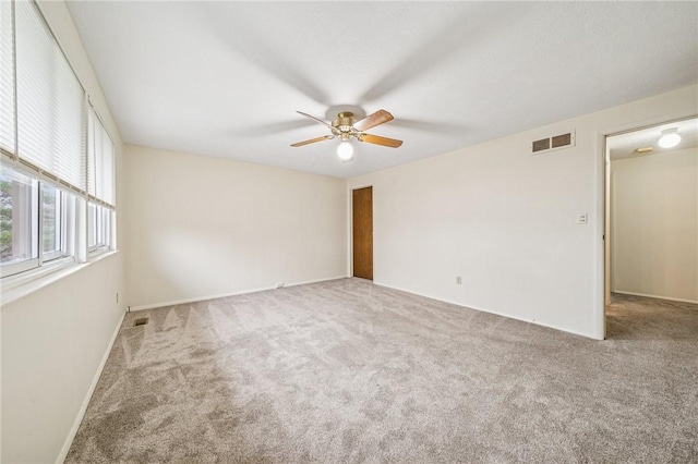 empty room featuring carpet flooring, baseboards, a ceiling fan, and visible vents