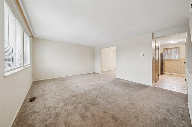 spare room with visible vents, baseboards, and light carpet