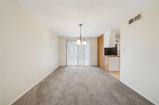 unfurnished room with a notable chandelier, visible vents, light colored carpet, and baseboards