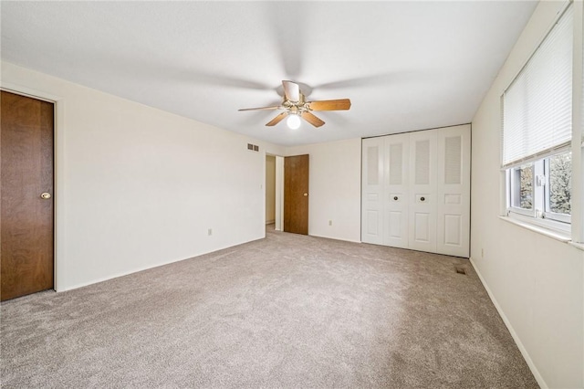 unfurnished bedroom featuring a closet, a ceiling fan, visible vents, and carpet floors