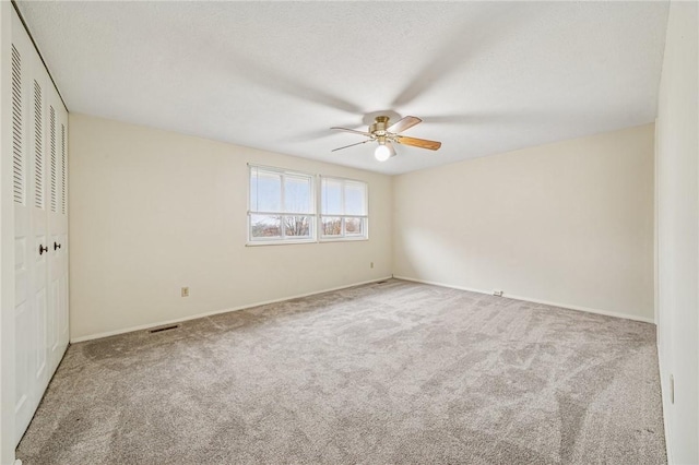 unfurnished bedroom with carpet, a closet, a ceiling fan, visible vents, and baseboards