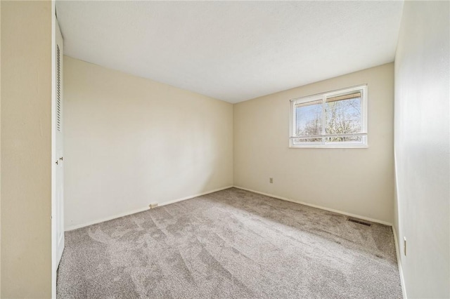 empty room with visible vents, baseboards, and carpet