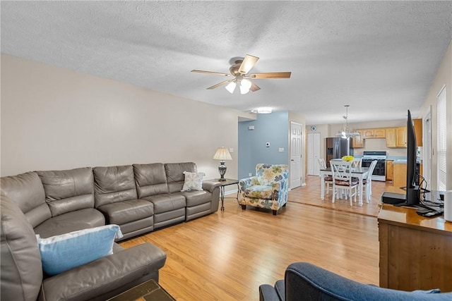 951 Castlegate Cir, Hempfield Twp, PA 15601 - living room with light wood finished floors, a ceiling fan, a chandelier, and a textured ceiling