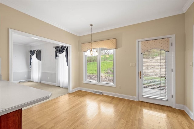 unfurnished dining area featuring a notable chandelier, baseboards, light wood-type flooring, crown molding, and visible vents