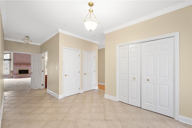 unfurnished bedroom with a closet, baseboards, ornamental molding, and a brick fireplace