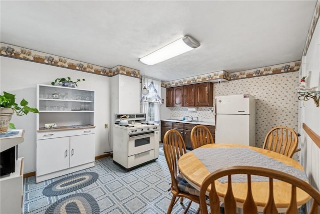 kitchen with a sink, light countertops, white appliances, dark brown cabinetry, and light floors
