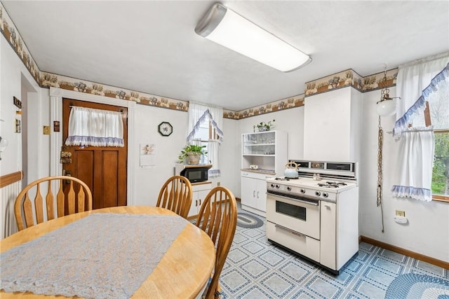 kitchen with baseboards and white gas range oven