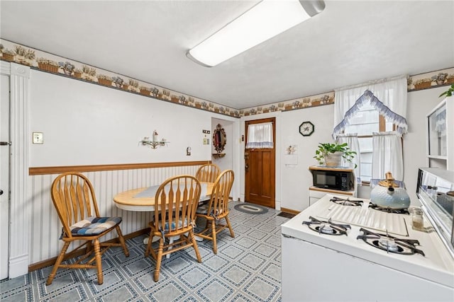 kitchen with white gas stove, black microwave, and light floors