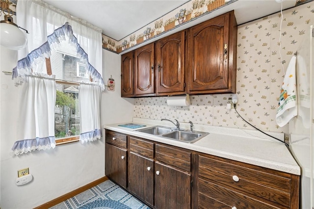 kitchen with baseboards, dark brown cabinetry, light countertops, and a sink