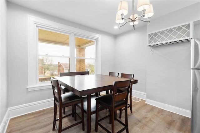 dining space with plenty of natural light, baseboards, an inviting chandelier, and wood finished floors
