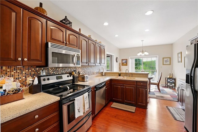105 Hillcrest Rd, Penn Twp But, PA 16053 - kitchen with appliances with stainless steel finishes, a sink, wood finished floors, a chandelier, and tasteful backsplash