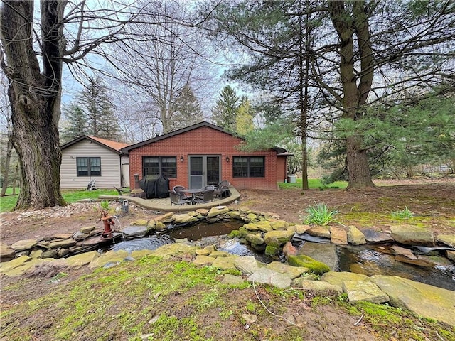 back of property with a small pond and brick siding