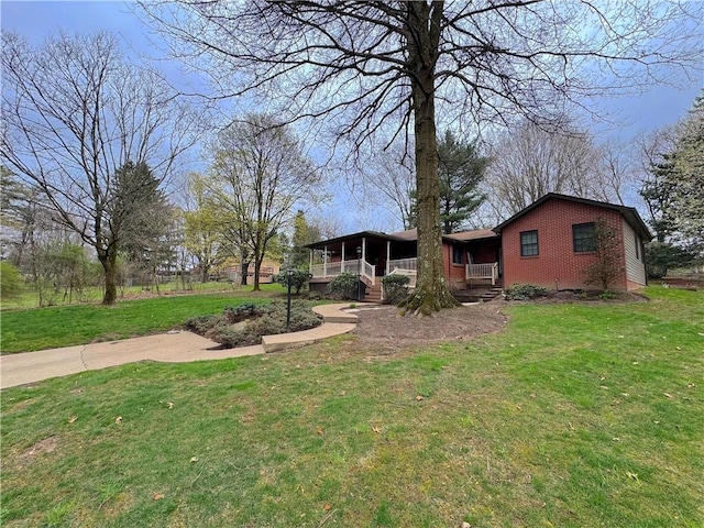 view of front of home with a sunroom, a front yard, and brick siding
