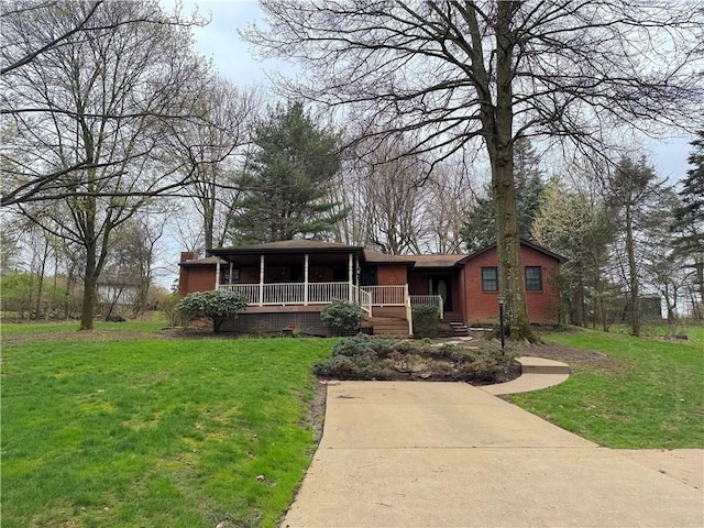 single story home with a chimney, covered porch, a front yard, and brick siding