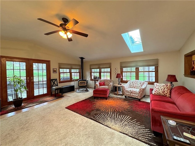 living area featuring french doors, vaulted ceiling with skylight, a wood stove, and a wealth of natural light