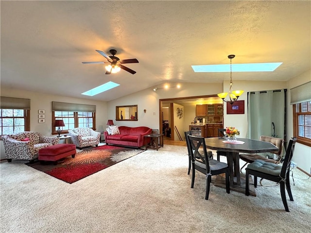dining space with light carpet, a ceiling fan, and lofted ceiling with skylight