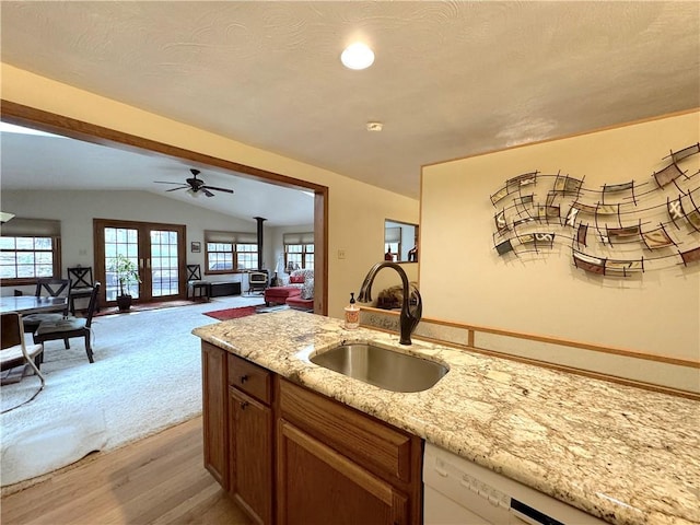 kitchen with lofted ceiling, light stone countertops, ceiling fan, white dishwasher, and a sink