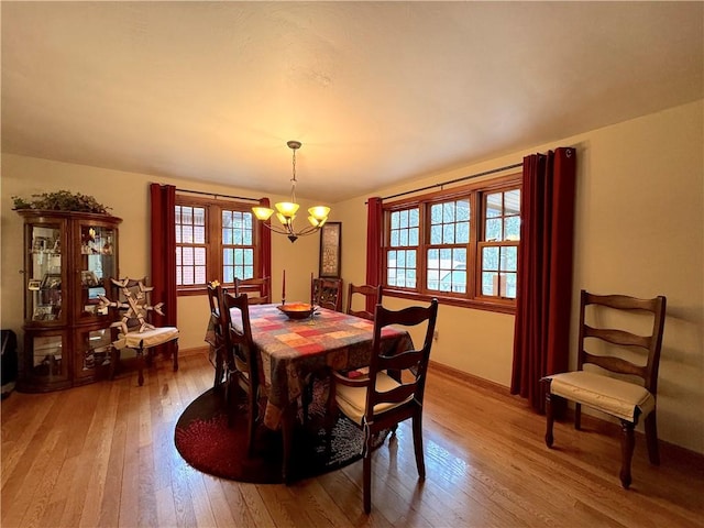 dining space featuring baseboards, hardwood / wood-style flooring, and an inviting chandelier