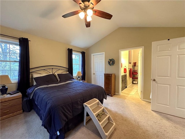 bedroom with light colored carpet, ceiling fan, ensuite bathroom, and vaulted ceiling