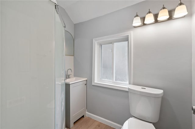bathroom featuring baseboards, toilet, vanity, vaulted ceiling, and wood finished floors