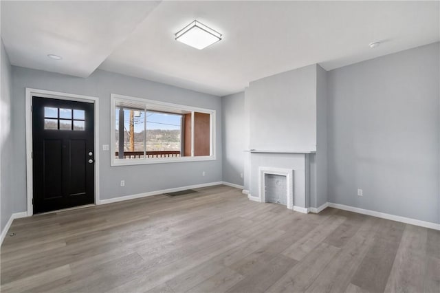 unfurnished living room featuring baseboards, wood finished floors, and a fireplace