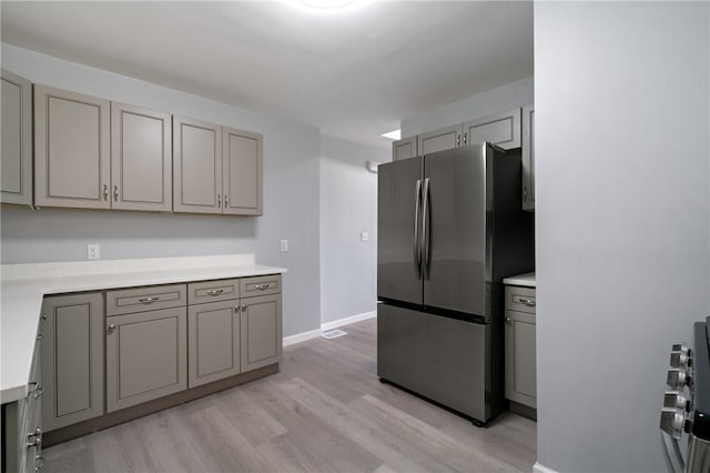 kitchen featuring gray cabinets, freestanding refrigerator, light countertops, and light wood-style flooring