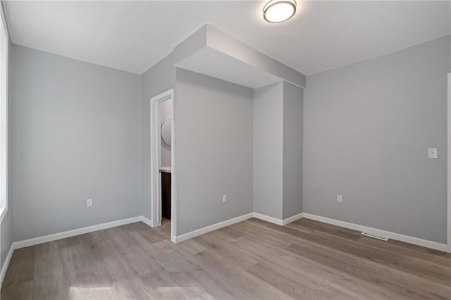 unfurnished bedroom with visible vents, light wood-style flooring, and baseboards