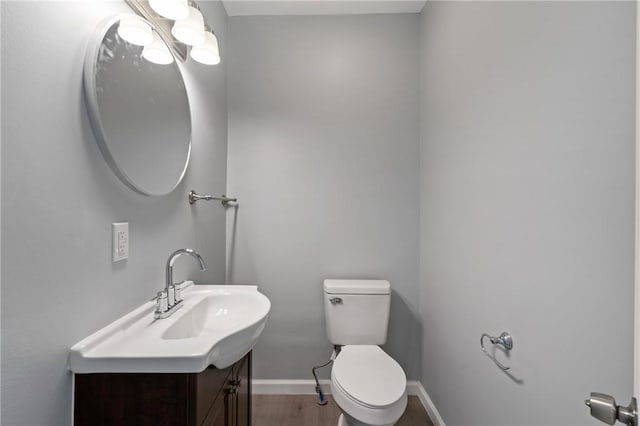 bathroom with toilet, wood finished floors, vanity, and baseboards