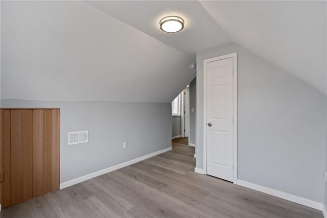 bonus room with wood finished floors, baseboards, lofted ceiling, and visible vents