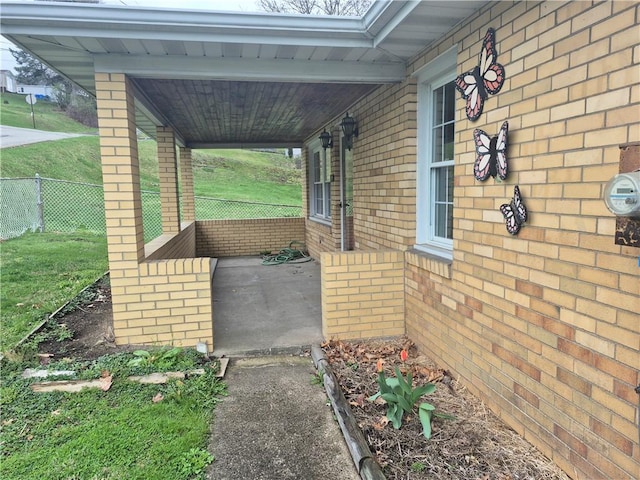 exterior space with brick siding, a porch, and fence